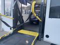 A yellow wheelchair lift is extended from a 2017 Chevrolet Express van with black safety straps positioned for securing passengers