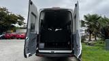 A 2017 Ford Transit van with open rear doors revealing black seats in the interior