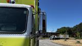 A 1995 Freightliner FLL086 truck with a bright yellow cab and chrome side mirror visible in the foreground