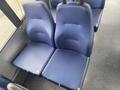 A pair of blue upholstered seats with a textured finish designed for a bus or van with visible wear and tear on the edges