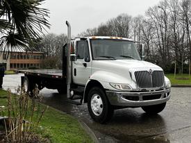 A 2011 International DuraStar 4300 truck with a flatbed and chrome details parked on a wet surface