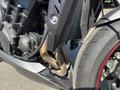 Close-up of a 2018 Triumph Street Triple RS showcasing the engine and exhaust system with a focus on the metallic components and the tire with red accents