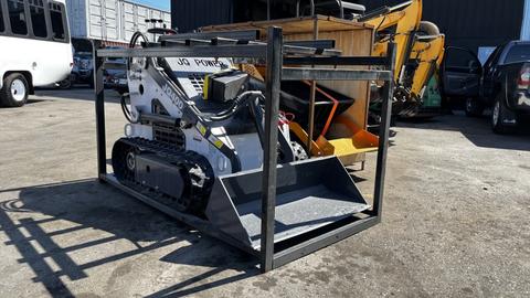 A 2024 JQ Power J Q 400 Stand Up machine with tracks and a front bucket, positioned within a metal frame for display