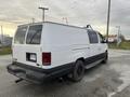 A white 2001 Ford Econoline van with a black bottom and black wheels parked at an angle