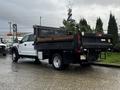 A 2021 Ford F-550 with a flatbed rear and a black cargo area is parked with a small load of plants in the back