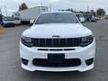 A white 2018 Jeep Grand Cherokee facing forward with a distinctive grille and headlights visible