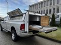 A 2012 RAM 3500 pickup truck with an open bed cover and a sliding toolbox attached to the side of the bed