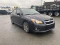 A 2014 Subaru Impreza in gray with a sleek design and alloy wheels parked on a wet surface