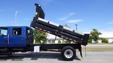 A blue 2012 International DuraStar 4300 dump truck with its bed raised, showing a black dump bed attached to the chassis