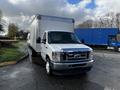 A 2021 Ford Econoline truck with a large white cargo box on the back and a silver front grille visible in the foreground