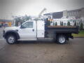 A white 2008 Ford F-550 flatbed truck with a tool storage compartment on the side and a flat loading area in the back