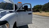 A white 2019 RAM 3500 with an open driver's door and an amber light on the roof