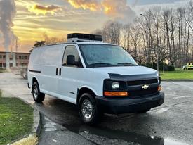 A 2005 Chevrolet Express van in white with a black grille and rooftop unit parked on a street