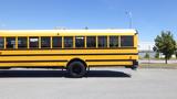 A yellow 2014 International 3000 school bus parked with its side view visible and windows displaying signs