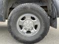 A close-up of a silver alloy wheel with a textured black tire on a 2010 Dodge Ram