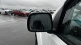 A 2016 Nissan Frontier is parked with raindrops on its side mirror reflecting surrounding vehicles