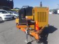 A yellow O'Brien 3515-CF trailer jetter with a black engine cover and a safety cone positioned in front attached to a trailer hitch