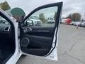 A 2018 Jeep Grand Cherokee with the driver's side door open showcasing the interior design and controls