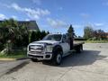 A 2013 Ford F-450 SD with a flatbed in the foreground