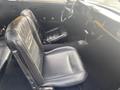Interior of a 1966 Ford Mustang featuring black leather seats and a classic steering wheel