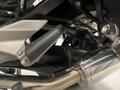 A close-up view of the exhaust system of a 2013 BMW K1600GTL featuring the muffler pipe and rear footpeg assembly