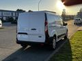 A white 2022 Ford Transit Connect van with a black lower section viewed from the rear on a paved road