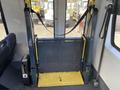 A yellow and black wheelchair lift in a van with a foldable platform and safety straps positioned upright in the foreground