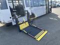 A 2017 Chevrolet Express bus with a deployed wheelchair ramp in the foreground