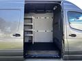 A 2021 Mercedes-Benz Sprinter van with an open rear door showing a spacious cargo area equipped with metal shelving and a light-colored interior panel