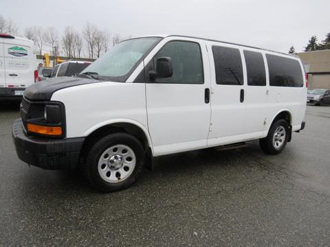 A white 2012 Chevrolet Express cargo van with a black front hood and multiple side windows