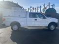 A white 2013 Ford F-150 truck with a utility box in the bed and 4x4 branding on the side