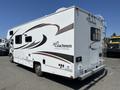 A white 2012 Ford Econoline camper van with decorative graphics on the side and a rear ladder for access to the roof