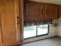 A 2012 Ford Econoline interior featuring wooden cabinets above a patterned fabric window shade