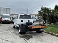 A white 2018 RAM 3500 truck with a flatbed design parked in a lot showing the rear view and spare tire mounted in the bed