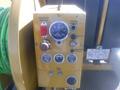 A yellow control panel featuring various dials switches and lights including a low water warning indicator and a power outlet on a trailer jetter