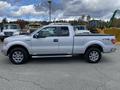 A silver 2013 Ford F-150 XTR with chrome wheels and a double cab is parked, showcasing its side profile and sturdy design