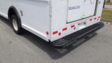 A white 2011 Ford Econoline with a rear step bumper and red reflective tape on the back doors