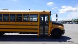 A yellow 2014 International 3000 school bus viewed from the side with large windows and a door open on the front side