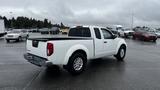 A white 2016 Nissan Frontier with a crew cab and cargo bed parked in a lot