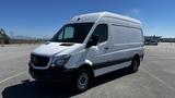 A 2016 Mercedes-Benz Sprinter van in white with a black stripe features a large cargo area and prominent front grille with the Mercedes logo