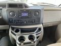 Interior view of a 2012 Ford Econoline dashboard showing the radio controls air conditioning dials and cup holders