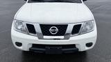 A white 2016 Nissan Frontier with a chrome grille and emblem prominently displayed at the front