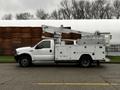 A 2004 Ford F-450 SD with a white exterior and a bucket lift mounted on the bed for aerial work