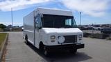 A white 2011 Ford Econoline cargo van with a large flat front and a single side mirror parked on a street