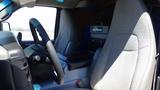 Interior of a 2012 GMC Savana displaying the steering wheel and driver's seat with gray upholstery and a console between the seats