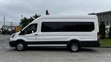 A white 2017 Ford Transit van with a high roof and black stripe along the side is displayed from a side view