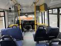 Interior of a 2018 Chevrolet Express bus featuring blue seats yellow handrails a dashboard and a rearview mirror