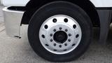 A close-up view of a silver alloy wheel with multiple holes and black lug nuts mounted on a black tire designed for a 2012 International TerraStar