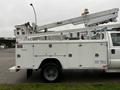 A white 2004 Ford F-450 SD truck with an Altec utility body and a raised aerial lift on the roof