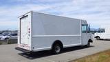 2011 Ford Econoline in white with a boxy cargo area and rear roll-up door parked in a lot